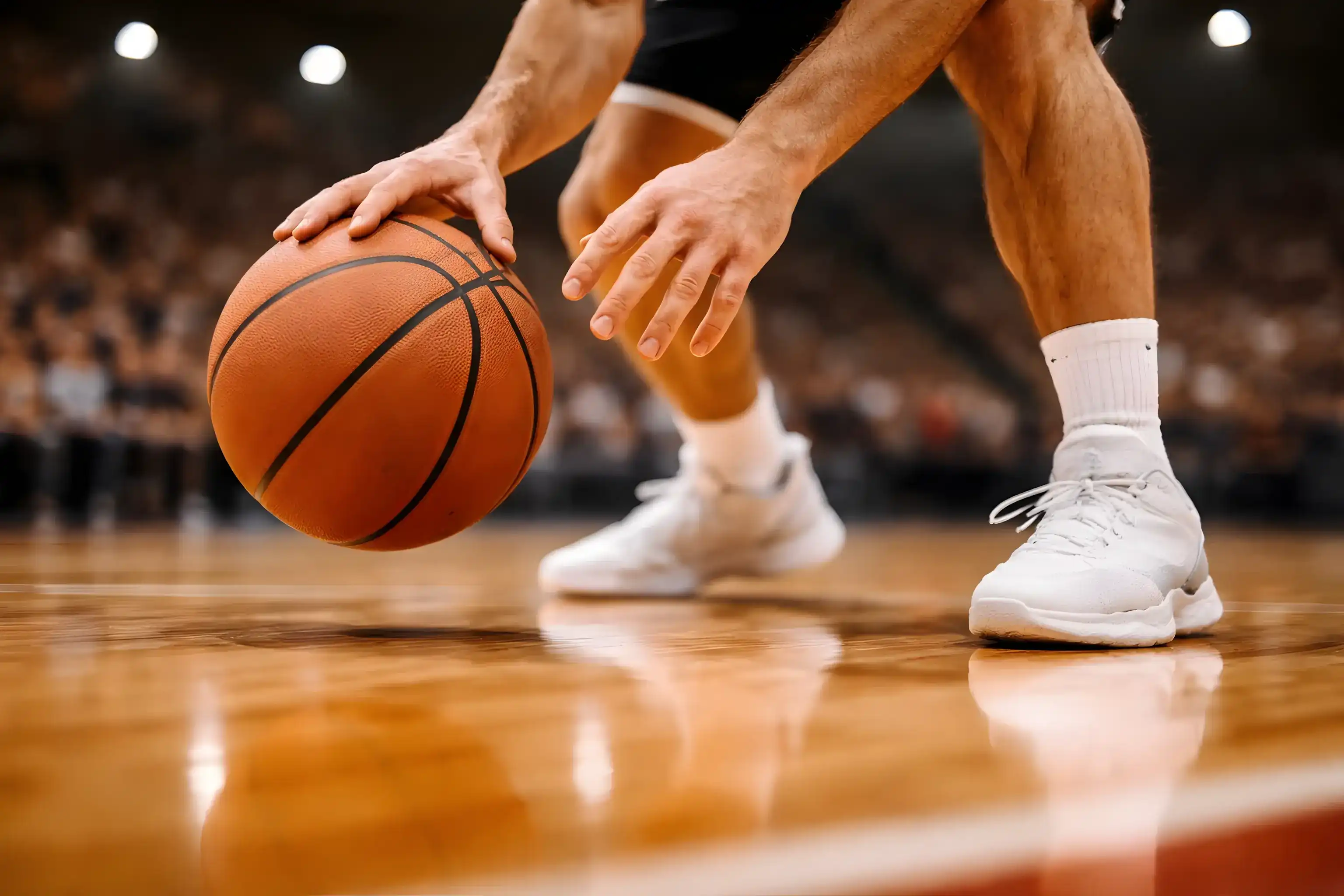 Κοντινό πλάνο παίκτη μπάσκετ που ντριμπλάρει την μπάλα στο παρκέ κατά τη διάρκεια αγώνα